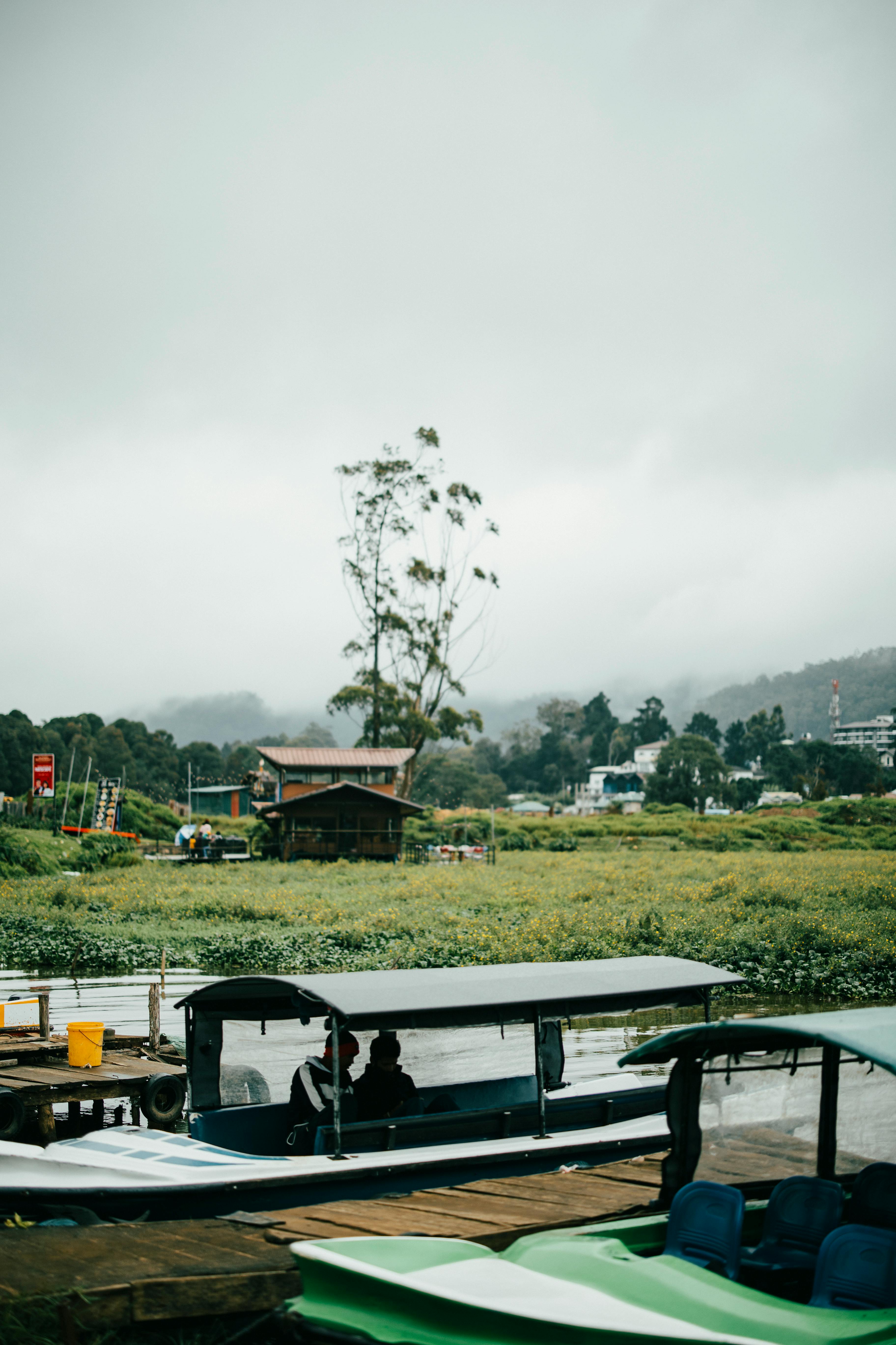 Colorful paddle boats on the calm waters of Gregory Lake in Nuwara Eliya, with surrounding green hills and blue skies