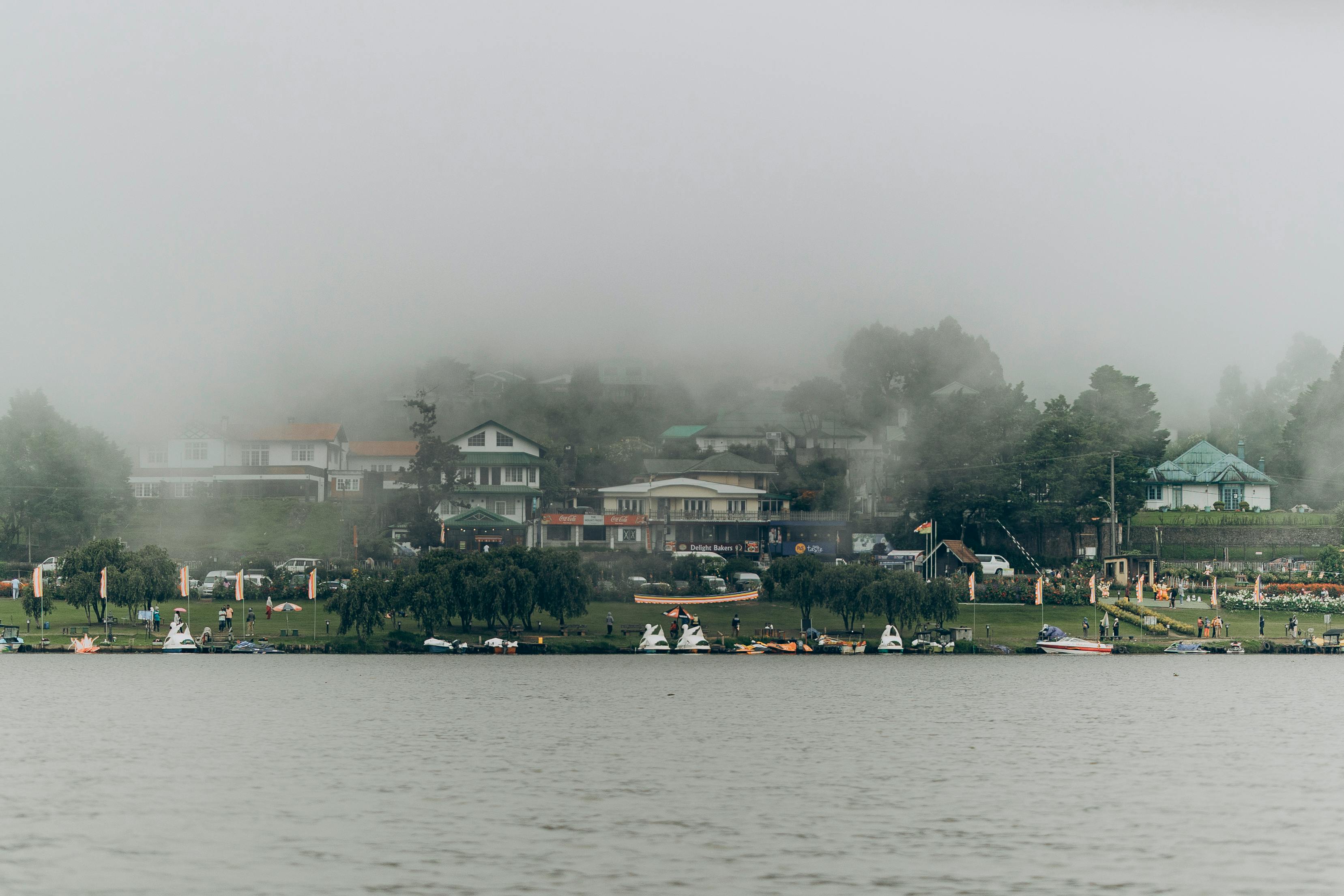 Picturesque cityscape of Nuwara Eliya, Sri Lanka with colonial buildings, a church steeple, and lush greenery under a cloudy sky